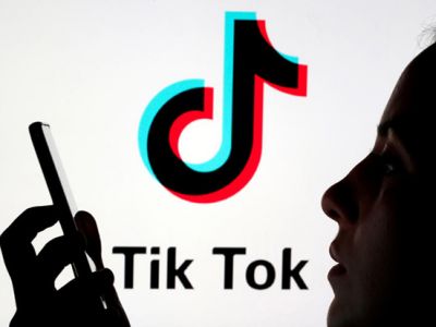 Человек держит смартфон, на фоне логотипа TikTok. Фото: Reuters